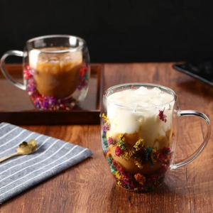 Xícara com flores secas servida com bebidas sobre uma mesa de madeira