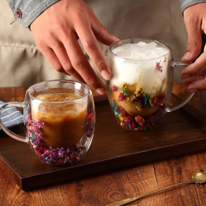 Duas xícaras com flores secas sobre uma bandeja de madeira