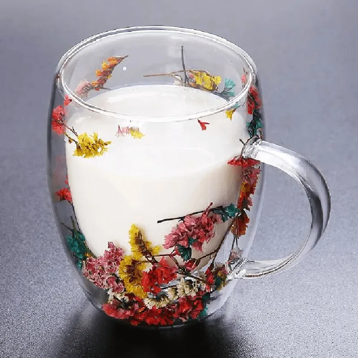 Foto-Caneca-Flor-Seca-CB-89372-Imagem-8.png Xícara com bebida clara e flores secas sobre fundo cinza