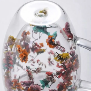 Detalhe da base da xícara com flores secas vistas através do vidro